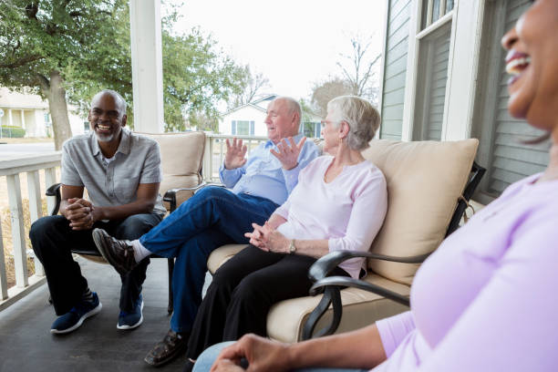 Diverse group relaxing on porch, chatting joyfully.