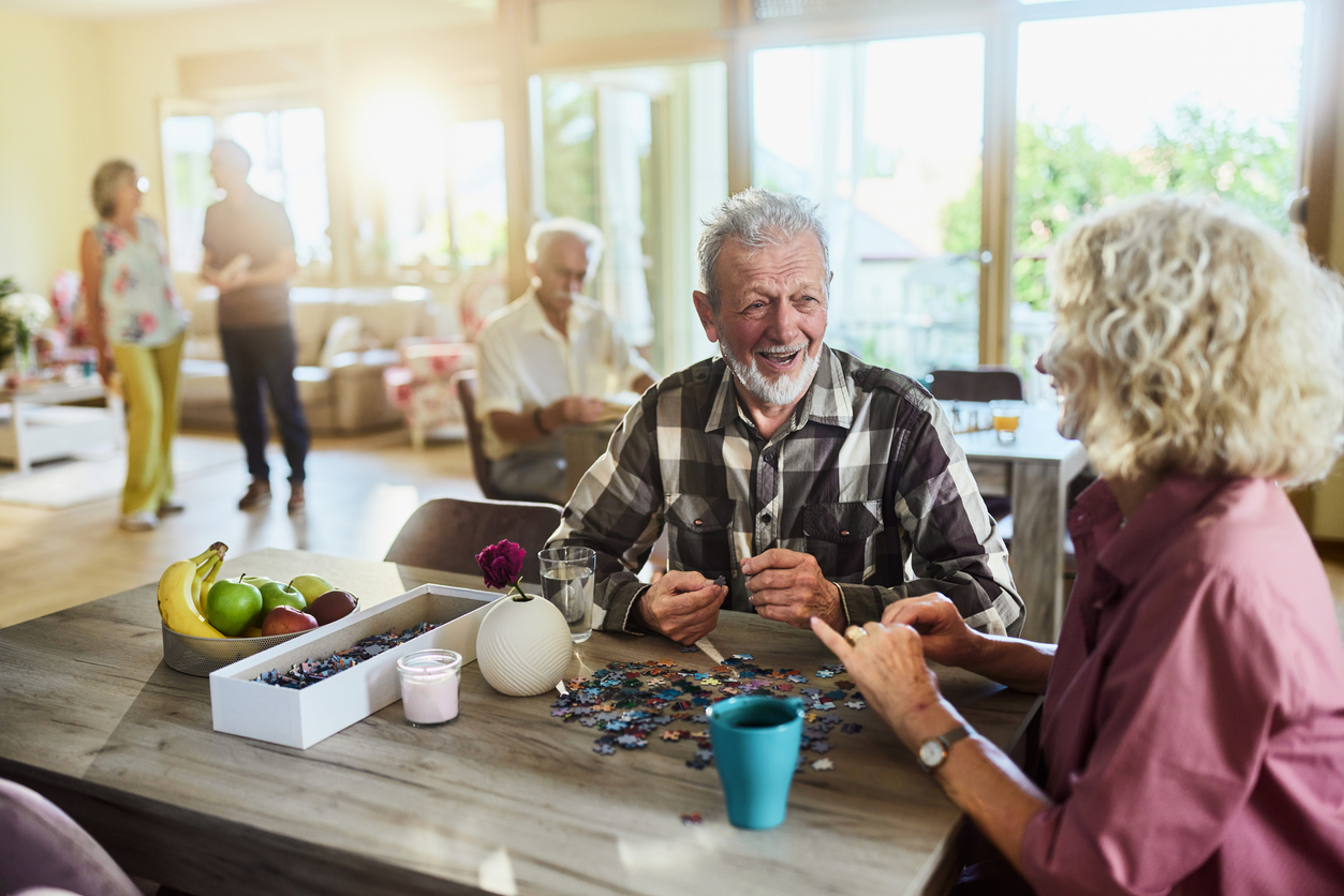 Elderly friends enjoying puzzle at home gathering.