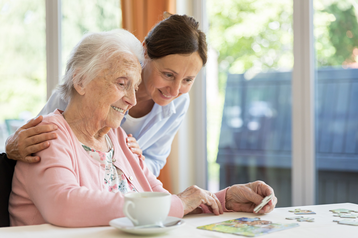 Elderly woman solving puzzle with assistance.
